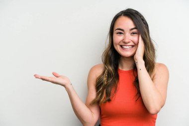 Beyaz arka planda izole edilmiş genç beyaz kadın avuç içinde fotokopi alanı tutuyor, el üstünde tutuyor. Şaşırmış ve mutlu..