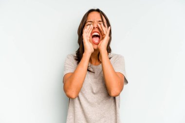 Mavi arka planda izole edilmiş genç İspanyol kadın elleriyle gözlerini kapatmaktan korkuyor..