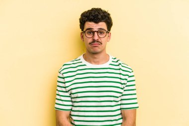 Kafkasyalı genç adam sarı arka planda izole edilmiş üzgün, ciddi yüzlü, mutsuz ve hoşnutsuz..