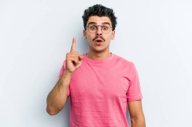 Mavi arka planda izole edilmiş beyaz bir adam ağzı açık bir şekilde üst tarafı işaret ediyor..