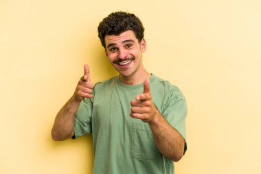 Sarı arka planda izole edilmiş genç beyaz adam öne bakan neşeli gülücükler.