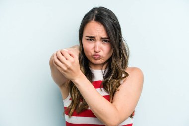 Genç beyaz kadın mavi arka planda izole edilmiş. Stres yüzünden boynu ağrıyor. Masaj yapıyor ve elle dokunuyor..