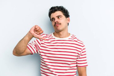 Mavi arka planda izole edilmiş genç beyaz bir adam hoşlanmadığı bir jest yapıyor. Anlaşmazlık konsepti.