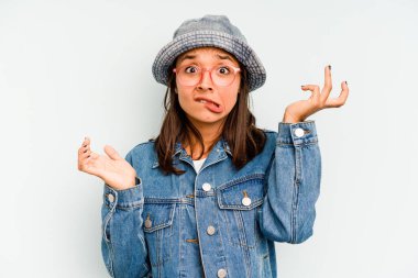 Genç İspanyol kadın mavi arka planda izole edilmiş. Gördüğü bir şey yüzünden şoka uğruyor..