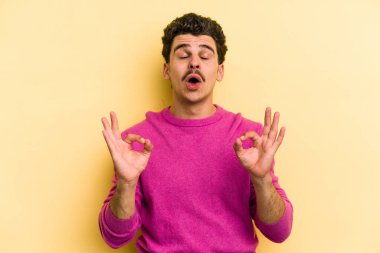 Sarı arka planda izole edilmiş genç beyaz adam sıkı çalışma gününden sonra rahatlıyor. Yoga yapıyor..