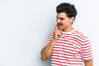 Mavi arka planda izole edilmiş genç beyaz adam rahatlamış bir şeyin fotokopi odasına baktığını düşünüyor..