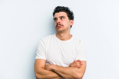 Mavi arka planda izole edilmiş genç beyaz adam tekrarlanan bir görevden yoruldu..