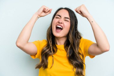 Genç beyaz kadın mavi arka planda izole edilmiş zafer sonrası yumruğunu kaldırıyor, kazanan konsept..