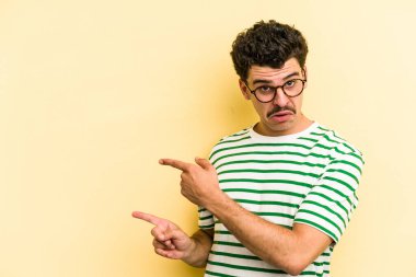 Sarı arka planda izole edilmiş genç beyaz adam işaret parmağıyla fotokopi alanını işaret ederek heyecan ve arzusunu ifade ediyor..