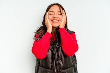 Mavi arka planda izole edilmiş genç İspanyol kadın elleriyle ağzını kapatırken şok oldu..