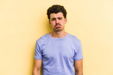 Kafkasyalı genç adam sarı arka planda izole edilmiş üzgün, ciddi yüzlü, mutsuz ve hoşnutsuz..