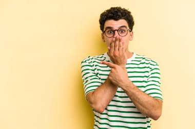 Sarı arka planda izole edilmiş genç beyaz adam yan tarafı işaret ediyor.