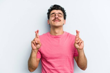 Kafkasyalı genç adam mavi arka planda izole edilmiş şans dilemek için şans diliyor.