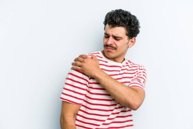 Mavi arka planda izole edilmiş, omuz ağrısı olan genç beyaz bir adam..