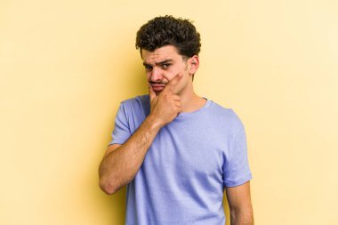 Kafkasyalı genç bir adam sarı arka planda izole edilmiş. Bir strateji planlıyor, bir iş yolu düşünüyor..