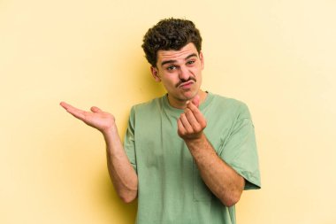 Sarı arka planda izole edilmiş genç beyaz adam, kadının hiç parası olmadığını gösteriyor..