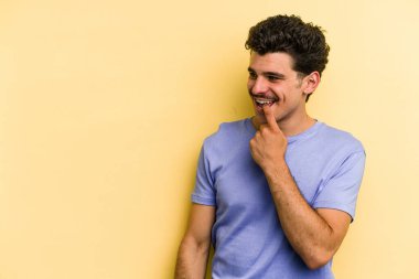 Sarı arka planda izole edilmiş genç beyaz adam rahatlamış bir şeyin fotokopi odasına baktığını düşünüyor..