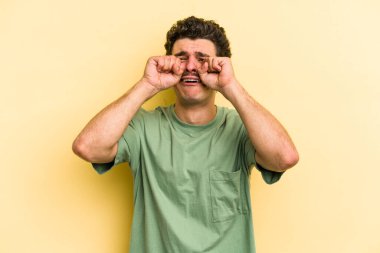 Kafkasyalı genç adam sarı arka planda izole edilmiş sızlanıyor ve ağlıyordu..