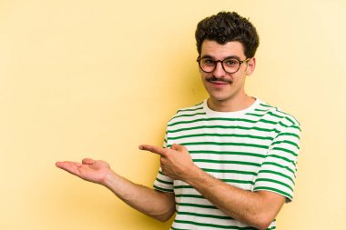 Sarı arka planda izole edilmiş genç beyaz bir adam, elinde bir fotokopi alanı tutarken heyecanlanıyor..