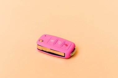 Pembe araba anahtarları bej arka planda izole edildi