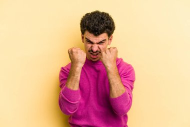 Sarı arka planda izole edilmiş genç beyaz adam gergin elleriyle çığlık atıyor..