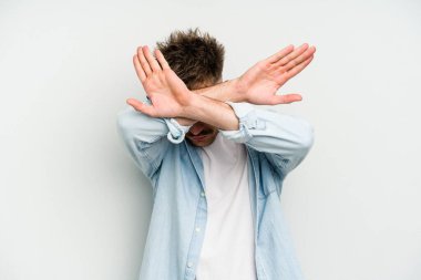 Beyaz arka planda izole genç beyaz adam iki kolu çapraz tutuyor, inkar kavramı.