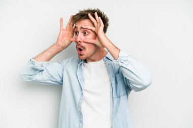 Beyaz arka planda izole edilmiş genç beyaz bir adam bir başarı fırsatı bulmak için gözlerini açık tutuyor..