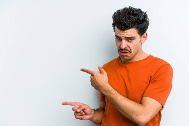 Mavi arka planda izole edilmiş genç beyaz adam işaret parmağıyla fotokopi alanını işaret ederek heyecan ve arzusunu ifade ediyor..