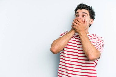 Kafkasyalı genç adam mavi arka planda izole edilmiş. Düşünceli bir şekilde ağzıyla ağzını kapatan bir fotokopi odasına bakıyor..