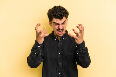 Sarı arka planda izole edilmiş genç beyaz adam öfkeyle bağırıyor..