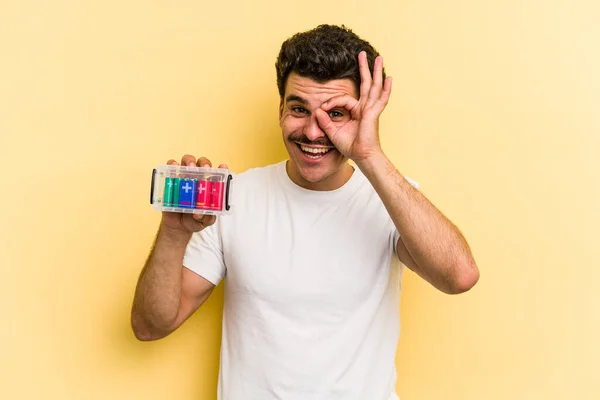 Young Caucasian Man Holding Batteries Isolated Yellow Background Excited Keeping — 스톡 사진