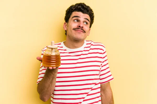 Young Caucasian Man Holding Honey Jar Isolated Yellow Background Dreaming — Stockfoto