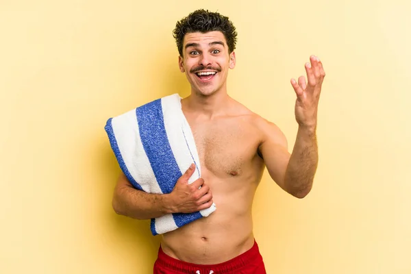 Young Caucasian Man Holding Beach Towel Isolated Yellow Background Receiving — Photo