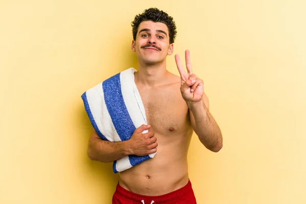 Young Caucasian Man Holding Beach Towel Isolated Yellow Background Showing — Stok fotoğraf