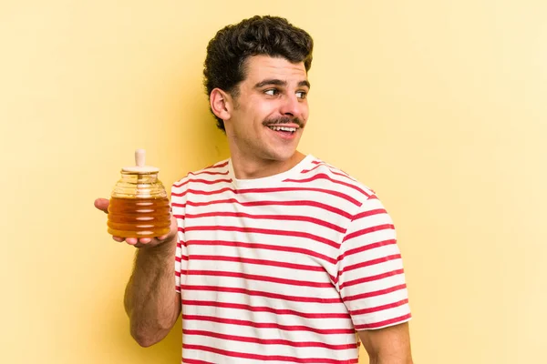 Young Caucasian Man Holding Honey Jar Isolated Yellow Background Looks — ストック写真