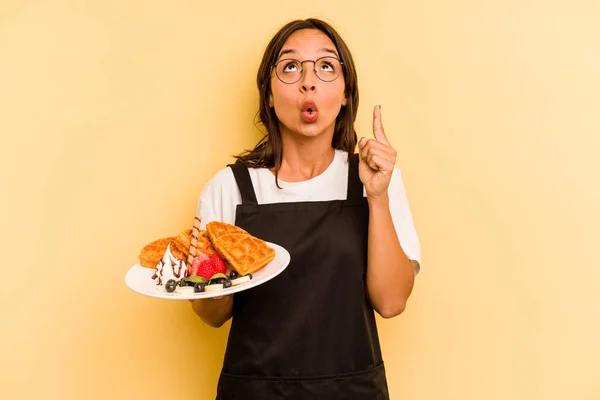Jovem Hispânico Dependente Mulher Segurando Waffles Isolado Fundo Amarelo Apontando — Fotografia de Stock