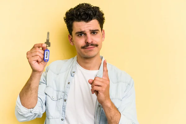 Young Caucasian Man Holding Home Keys Isolated Yellow Background Showing — Stockfoto