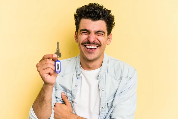 Young Caucasian Man Holding Home Keys Isolated Yellow Background Laughing — Stockfoto