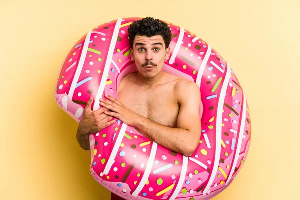 Young Caucasian Man Holding Inflatable Donut Isolated Yellow Background Shrugs — Stock fotografie