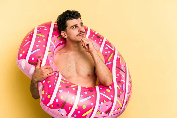 Young Caucasian Man Holding Inflatable Donut Isolated Yellow Background Looking — 图库照片