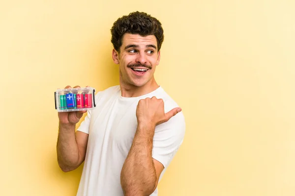 Young Caucasian Man Holding Batteries Isolated Yellow Background Points Thumb — Stock Fotó