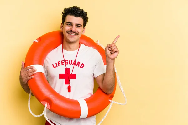 Young Caucasian Lifeguard Man Isolated Yellow Background Smiling Pointing Aside — ストック写真