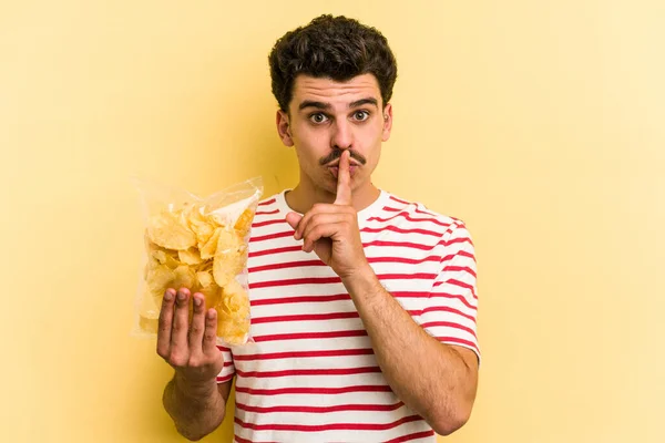 Young Caucasian Man Holding Bag Chips Isolated Yellow Background Keeping — Stockfoto