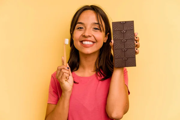 Молодая Испаноязычная Женщина Моет Зубы После Еды Шоколад Изолирован Желтом — стоковое фото
