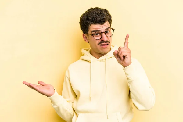 Young Caucasian Man Isolated Yellow Background Holding Showing Product Hand — Stock Photo, Image