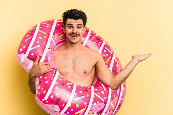 Young Caucasian Man Holding Inflatable Donut Isolated Yellow Background Showing — 图库照片