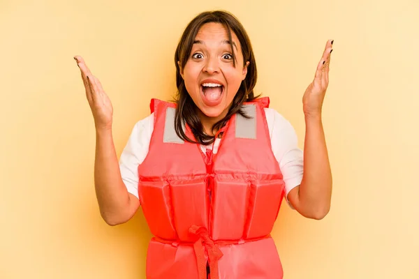 年轻的惊慌失措的女人 穿着黄色背景的救生衣 带着惊喜 兴奋地举起双手 — 图库照片