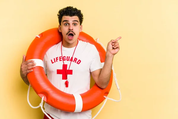 Young Caucasian Lifeguard Man Isolated Yellow Background Pointing Side — ストック写真