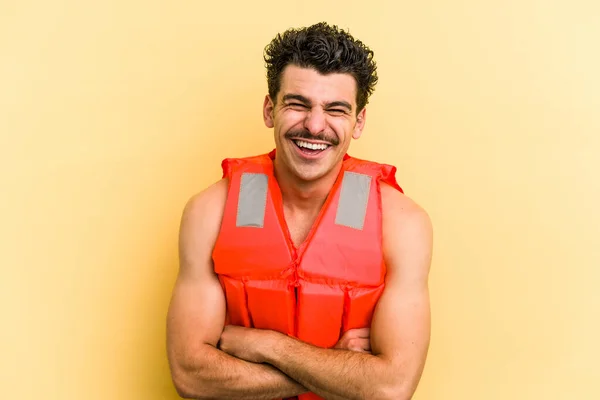 Young Caucasian Man Wearing Life Jacket Isolated Yellow Background Laughing — Fotografia de Stock