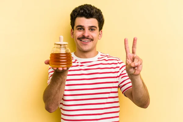 Young Caucasian Man Holding Honey Jar Isolated Yellow Background Showing — Stockfoto